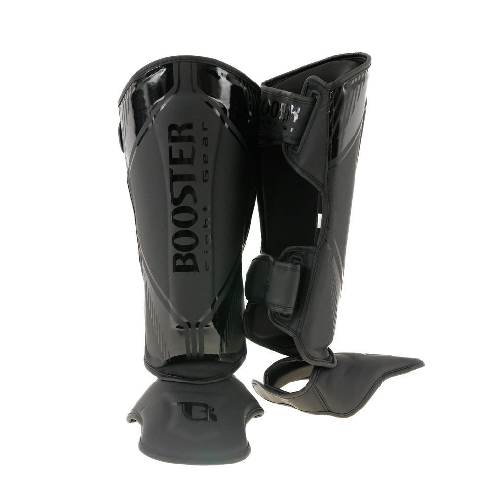 Booster Bangkok Scheenbeschermers Zwart, glanzend synthetisch leer met anatomische vorm, stevige schuimvulling en klittenbandsluiting.