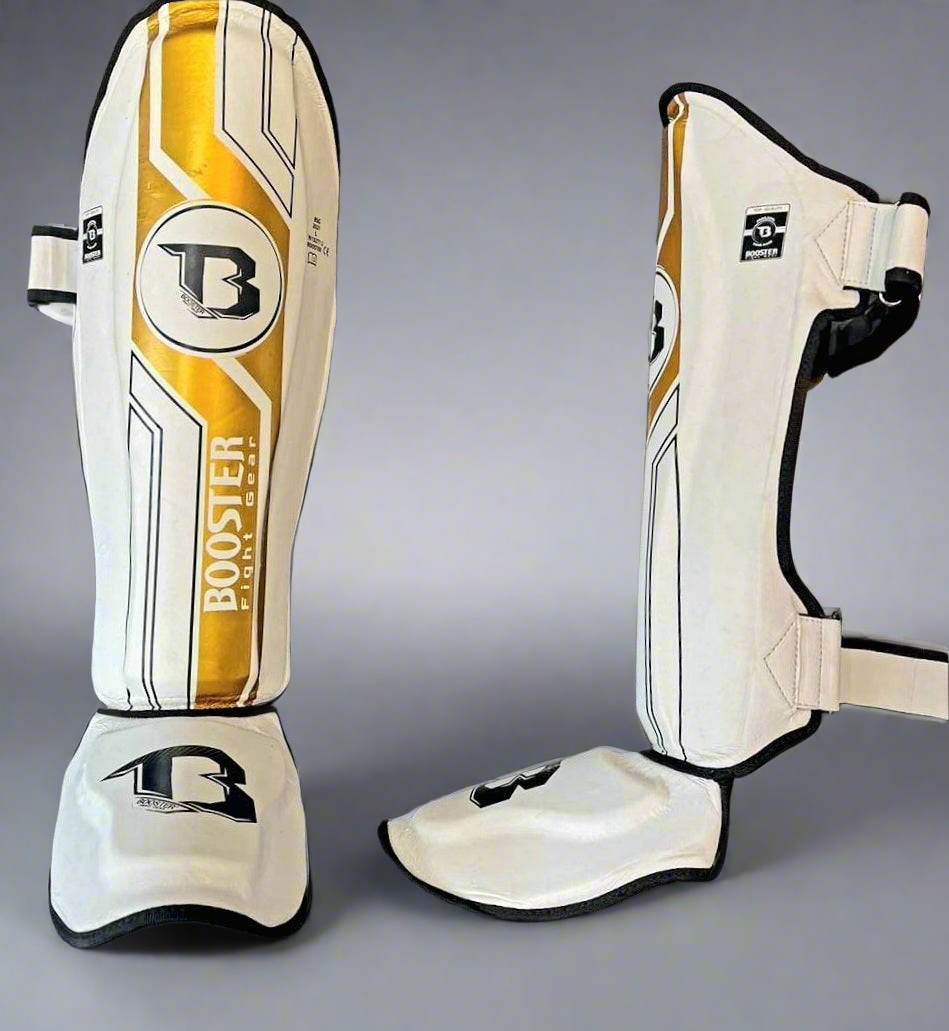 Booster V9 Kickboks Set Wit/Goud – wit-gouden BSG Pro V9 scheenbeschermers, voorzijde en zijaanzicht met sluitingen